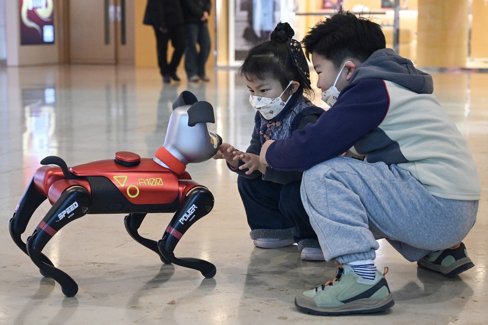 crianças interagindo com um cão de estimação de IA em uma loja da empresa de tecnologia Weilan em Nanquim, na província de Jiangsu, no leste da China. — Foto: Rita QIAN / AFP