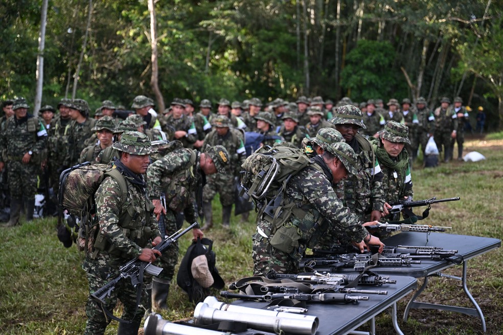 Membros do grupo guerrilheiro Coordinadora Nacional Ejército Bolivariano (CNEB) depõem suas armas em cerimônia de desarmamento no município de Valle del Guamuez, em Putumayo, na Colômbia, em 18 de junho de 2026. — Foto: Raul Arboleda/AFP