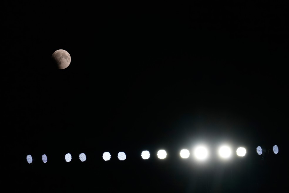 Eclipse lunar parcial � visto acima dos refletores do est�dio durante jogo de pr�-temporada da NFL entre New England Patriots e Cleveland Browns, em Cleveland, nos Estados Unidos, nesta quinta-feira (27). � Foto: Carolyn Kaster/AP
