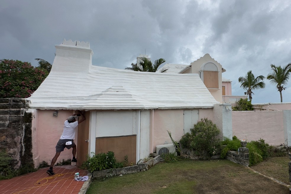 Homem tenta proteger casa do Furacão Ernesto em Warwick, Bermudas, na sexta (16) — Foto: Mary F. Calvert/via Reuters