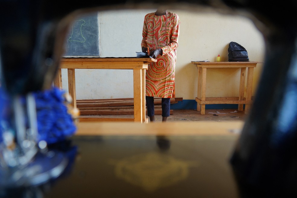 Uma aluna, ex-criança-soldado, corta um pedaço de tecido durante uma aula de costura no Centro de Alfabetização e Formação Profissional Prática de Bria. — Foto: MARIAM KONE / AFP
