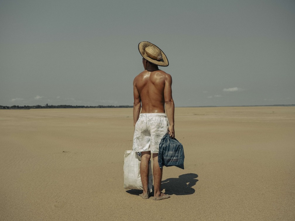 Um jovem leva comida para sua mãe, que mora na aldeia de Manacapuru, no Amazonas. A aldeia antes era acessível por barco, mas, por causa da seca, ele precisava caminhar 2 kms ao longo do leito seco do Rio Solimões para chegar até lá. Série de fotógrafo mexicano sobre a seca na Amazônia foi vencedora na categoria Histórias — Foto: Musuk Nolte/Panos Pictures/Bertha Foundation via World Press Photo/Divulgação