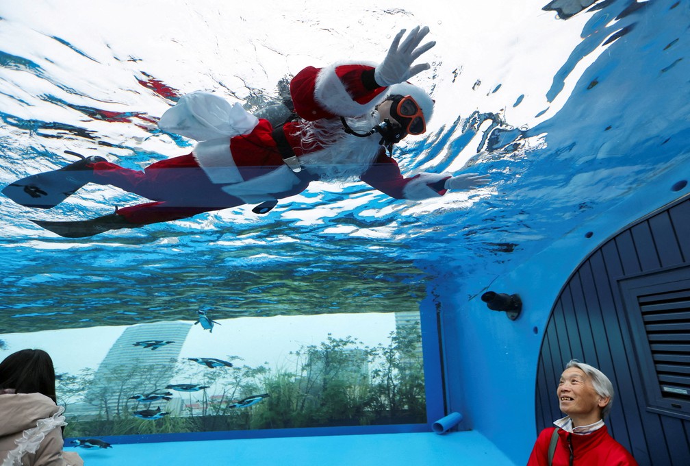 Uma mergulhadora vestida de Papai Noel nada dentro do tanque “Penguins in the Sky”, com pinguins-africanos, no Aquário Sunshine, em Tóquio, no Japão. — Foto: Reuters/Issei Kato