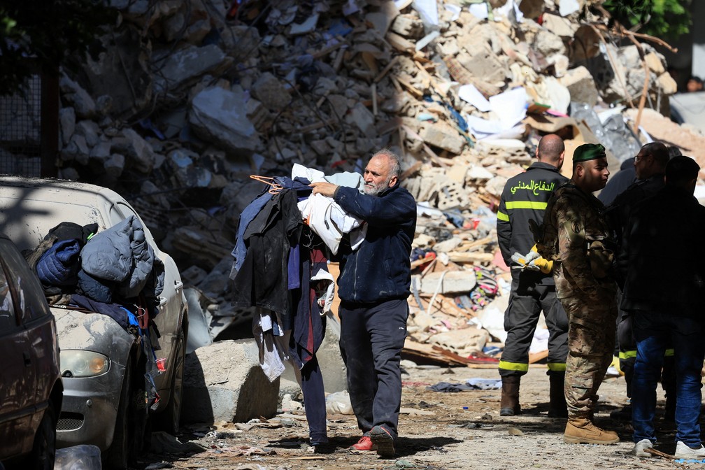 Homem carrega roupas próximo a escombros de prédio após ataque israelense no bairro de Ain Al Mraiseh, em Beirute, no Líbano, em 8 de abril de 2026. — Foto: REUTERS/Mohamed Azakir