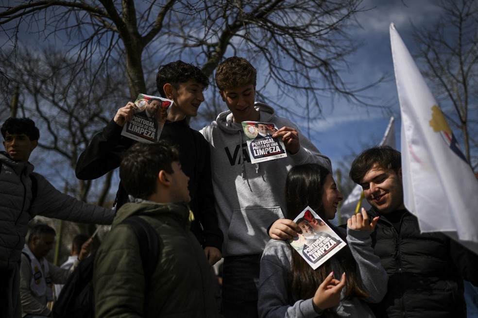 Jovens portugueses seguram folhetos com o slogan "Portugal precisa de uma limpeza" durante ato do partido de extrema direita Chega, em fevereiro de 2024. — Foto: Patrícia de Melo Moreira/ AFP