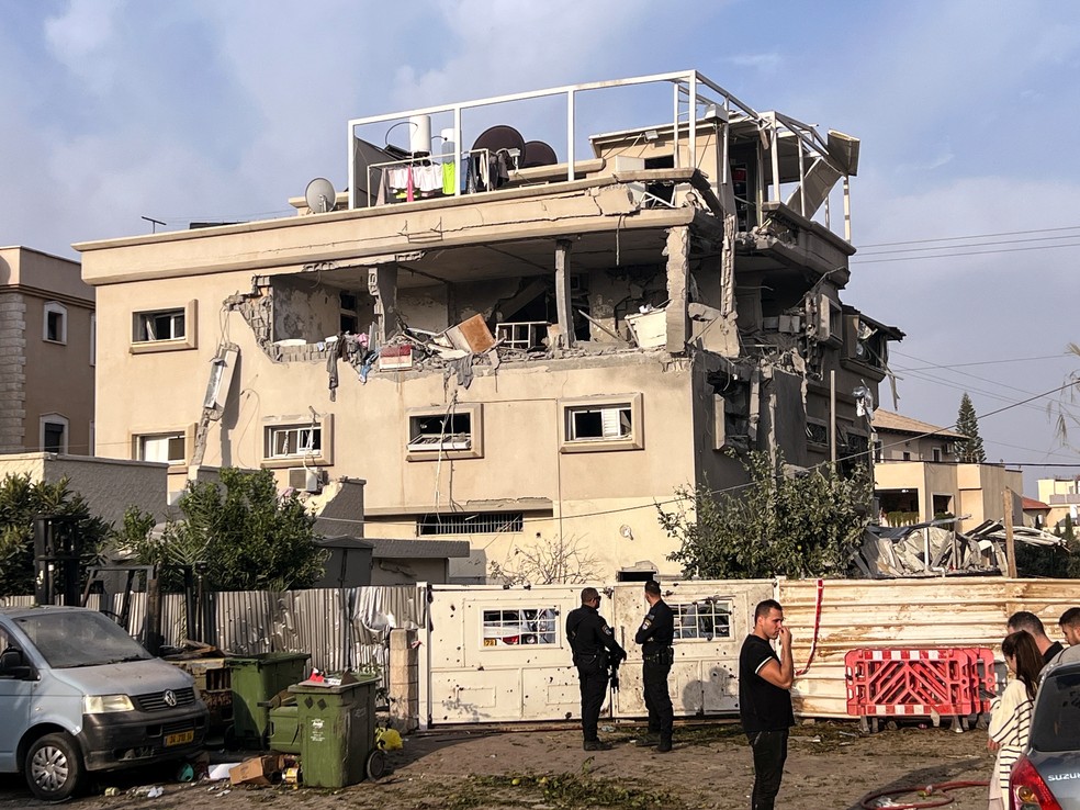 Moradores e autoridades policiais se reúnem perto de uma casa que foi atingida, após um ataque de projéteis do Líbano em direção a Israel, em Tira — Foto: Rami Amichay/Reuters
