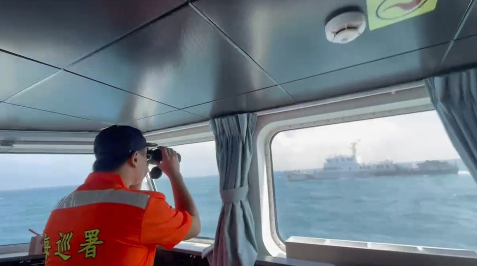 Guarda de Taiwan visualiza com binóculos navio de guerra chinês que navegou ao redor de Taiwan durante manobras militares de Pequim, em 14 de outubro de 2024. — Foto: Guarda Costeira de Taiwan via AP