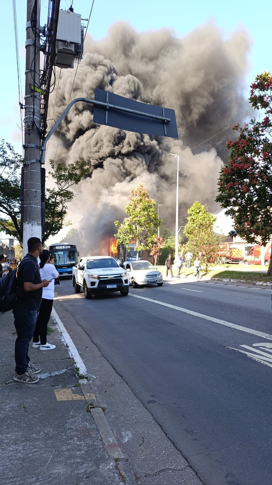 Ônibus articulado pega fogo no corredor que leva ao Terminal Jabaquara; chamas formam coluna de fumaça no céu