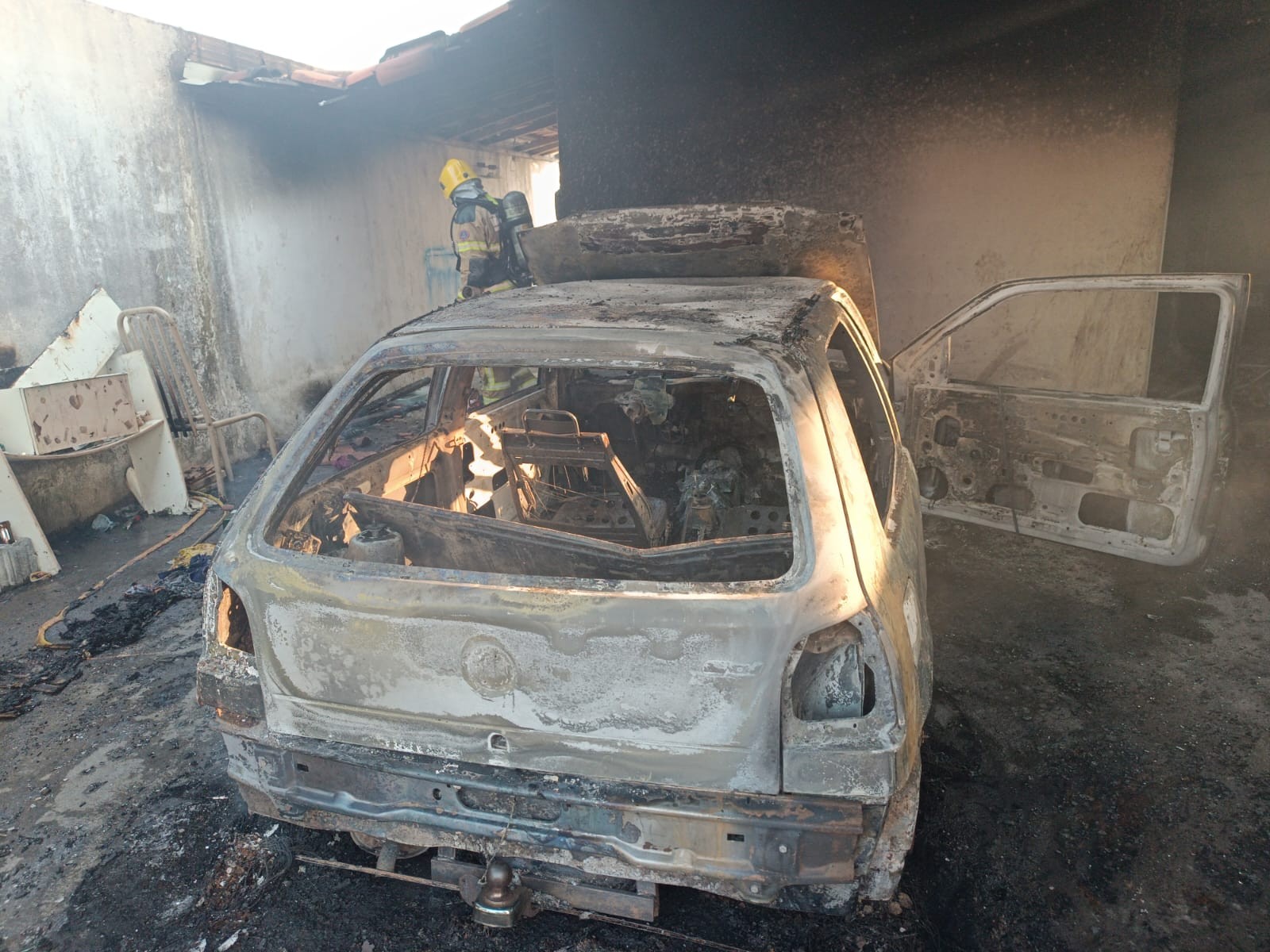 Carro fica destruído após pegar fogo em garagem de casa em Formiga 