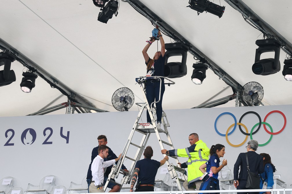 Funcion&aacute;rio tenta arrumar uma goteira antes da cerim&ocirc;nia de abertura das Olimp&iacute;adas de 2024 &mdash; Foto: Kai Pfaffenbach/Reuters