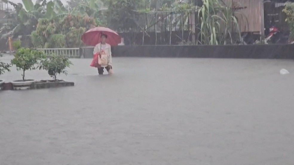 Um homem com um guarda-chuva permanece em meio à água da enchente durante as fortes chuvas causadas pela passagem do tufão Mekkhala em direção ao Japão. — Foto: CTS via REUTERS TV