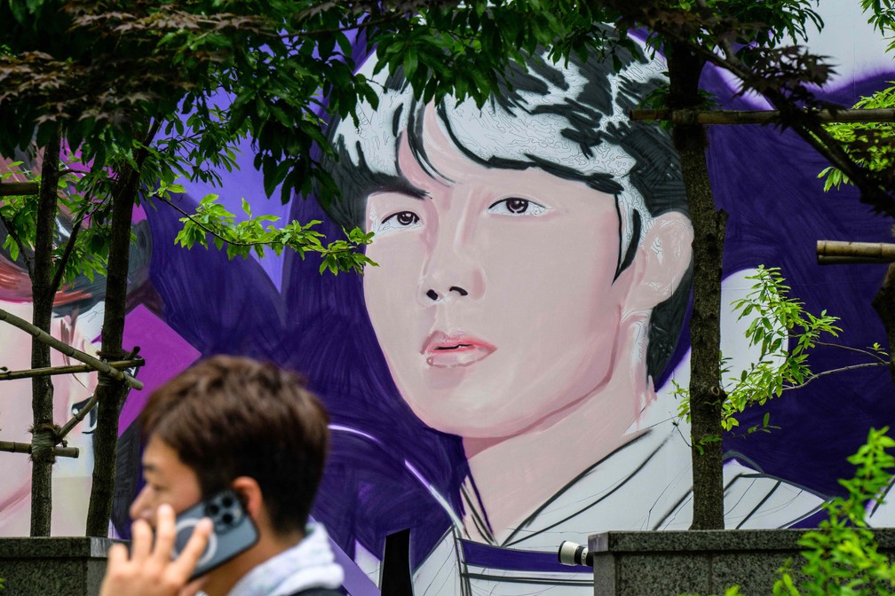 Mural com integrantes do BTS sendo pintado em celebração aos 10 anos do grupo — Foto: Anthony Wallace/AFP