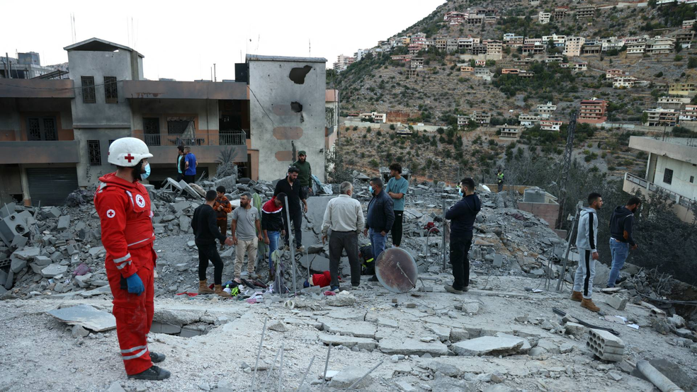 Integrantes do resgate e moradores observam destruição deixada por bombardeio israelense em Shebaa, no sul do Líbano, perto da fronteira com Israel — Foto: Rabih DAHER / AFP