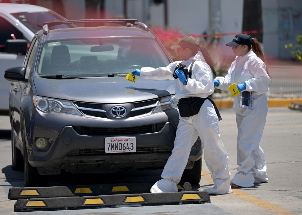 Policiais forenses inspecionam carro onde corpo foi encontrado perto do estádio Caliente, local de treino da seleção iraniana — Foto: Guillermo Arias/AFP