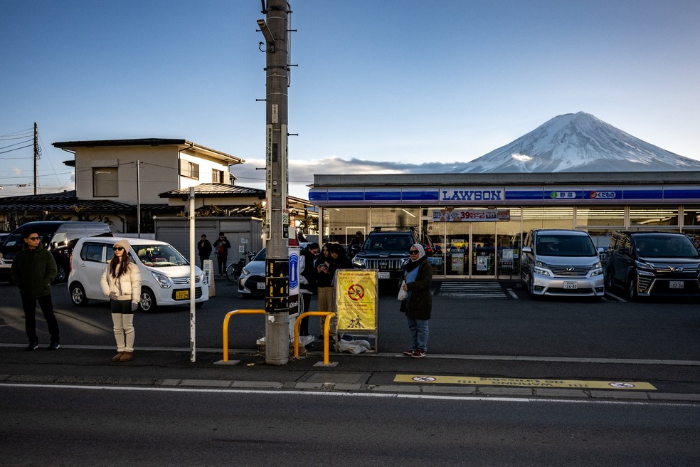 Turistas posam em frente a loja de conveniência em Fujikawaguchiko, para tirar fotos do Monte Fuji, no Japão — Foto: Philip Fong / AFP