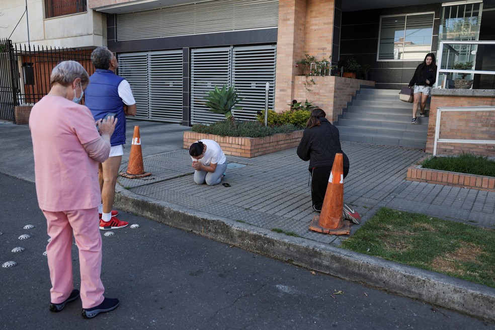 Uma mulher reza enquanto pessoas se re&uacute;nem do lado de fora de um pr&eacute;dio ap&oacute;s um terremoto em Bogot&aacute;, capital da Col&ocirc;mbia, em 10 de agosto de 2026. &mdash; Foto: Luisa Gonzalez/Reuters