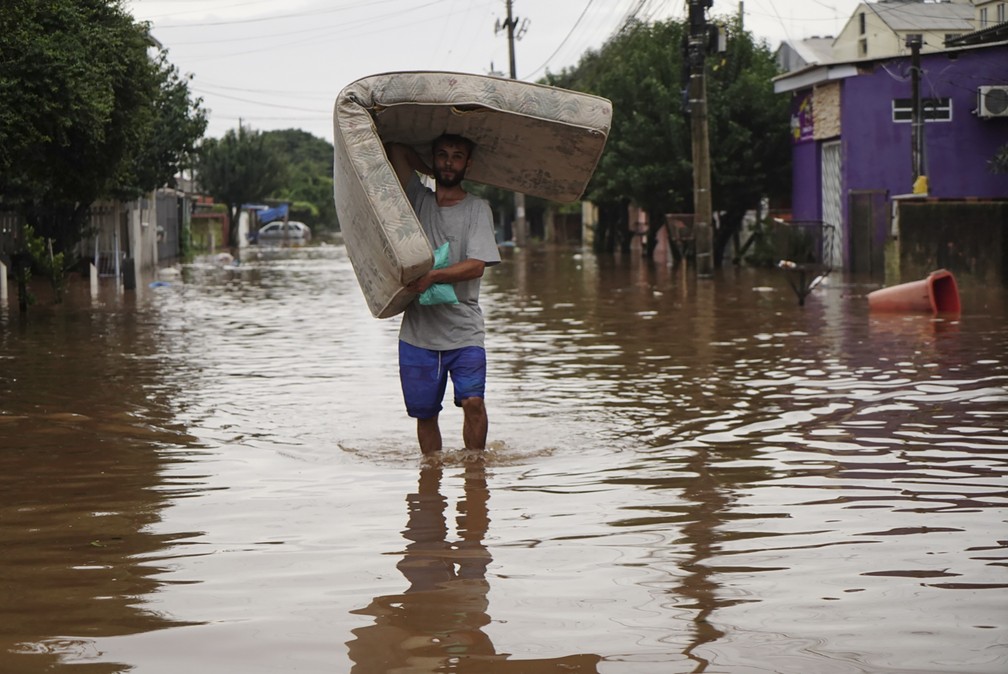 4 de maio - Homem carrega colchão em meio a rua inundada em Canoas, Rio Grande do Sul — Foto: Carlos Macedo/AP