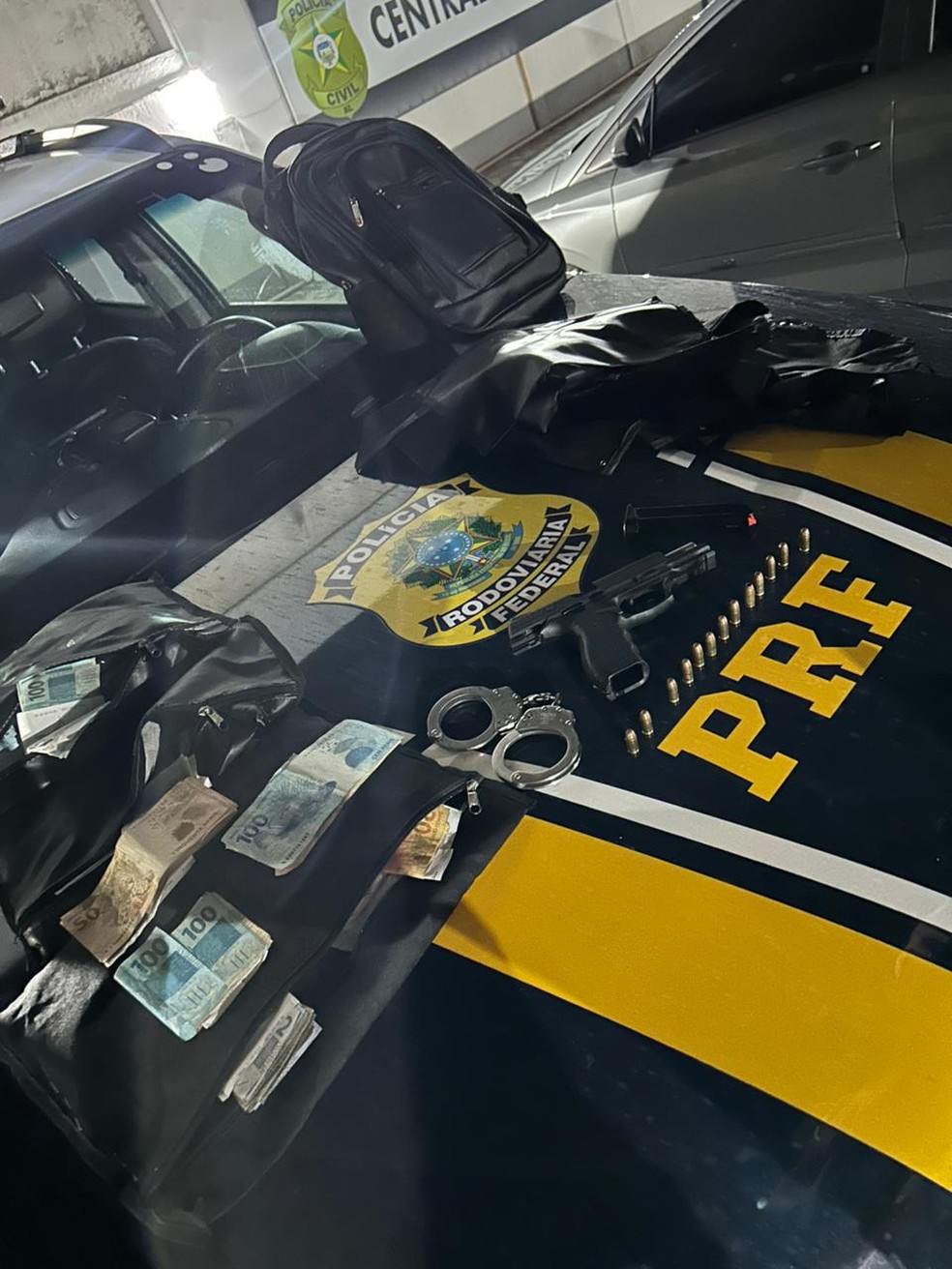 Material apreendido pela PRF em Maceió: arma, dinheiro e algemas.