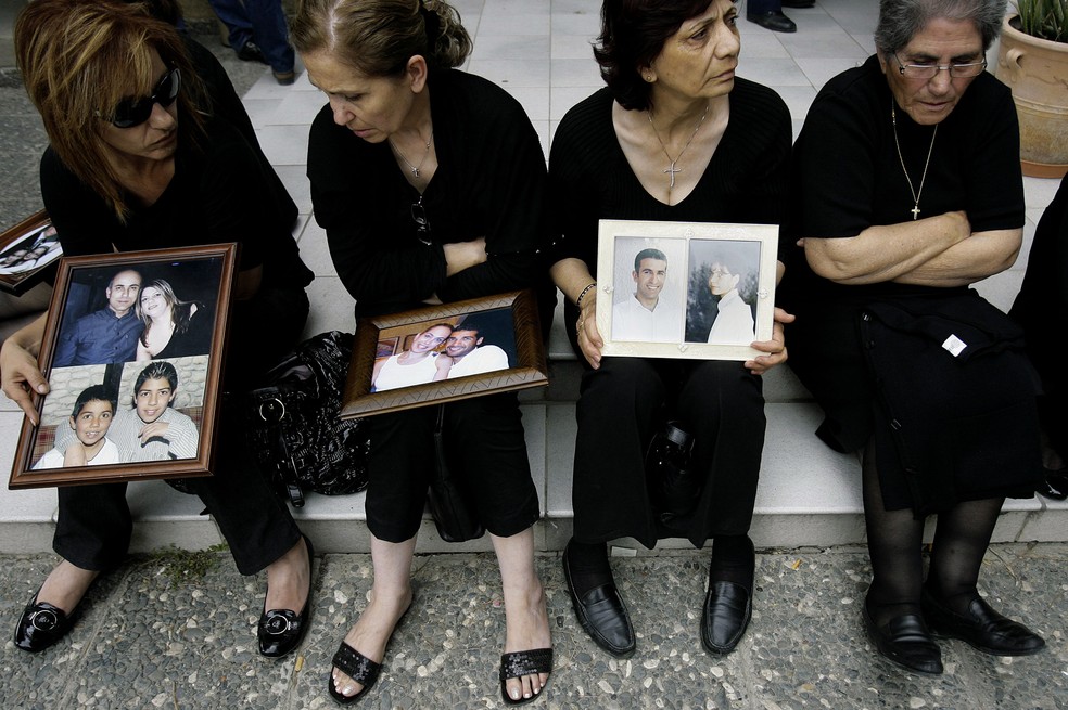 Familiares com retratos de vítimas do voo Helios 522, que caiu na Grécia em 2005 — Foto: Petros Karadjias/AP