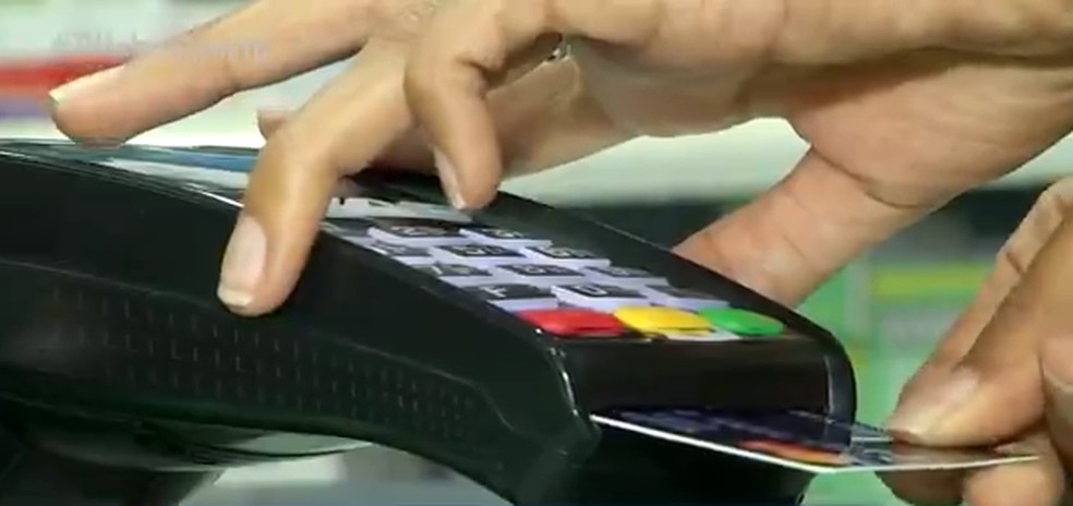 Pessoa passando compra com o cartão de crédito — Foto: TV Anhanguera/Divulgação