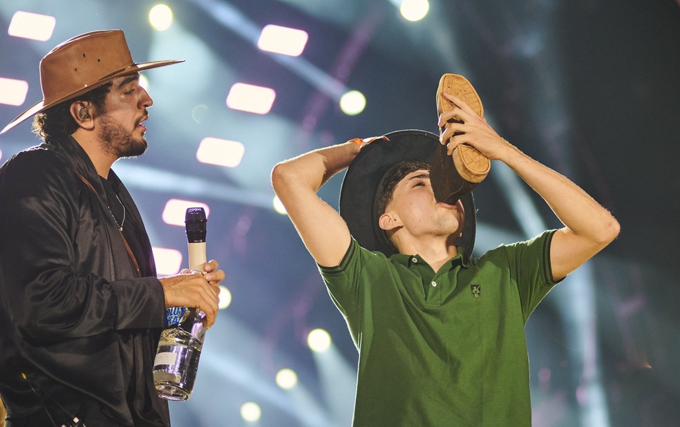 Fã toma bebida na bota servida por Nattan no palco do Ribeirão Rodeo Music 2025 em Ribeirão Preto, SP — Foto: Érico Andrade/g1