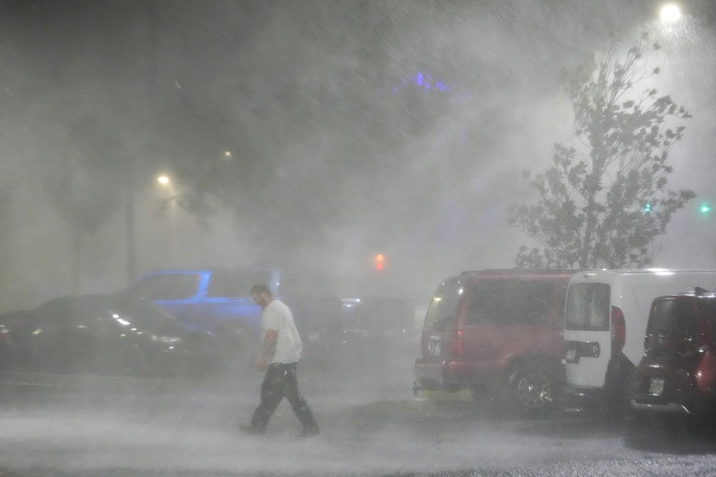 Homem caminha em estacionamento durante a passagem do furacão Milton em Tampa, na Flórida — Foto: Julio Cortez/AP