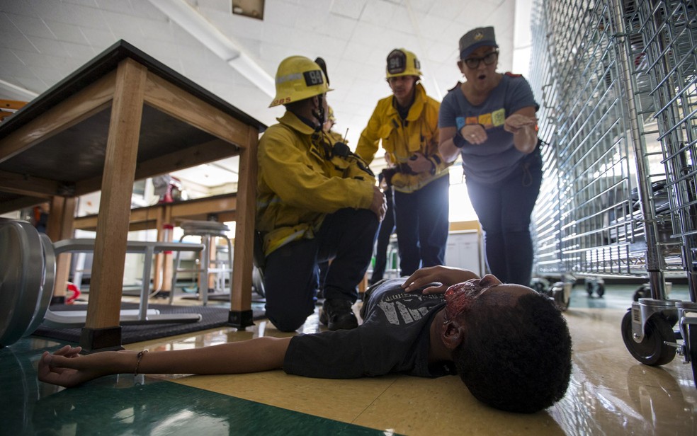 Bombeiros e um intérprete ajudam um estudante que finge estar ferido durante uma simulação de terremoto na Califórnia — Foto: Mario Anzuoni/Reuters