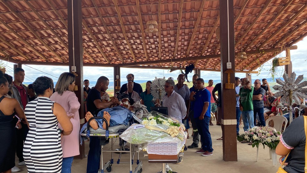 Deitada em maca, sobrevivente acompanha velório de filha em acidente com 25 mortos na Bahia — Foto: Filipe Costa