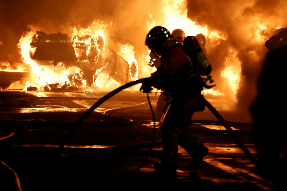 Bombeiros tentam apagar fogo aps manifestantes incendiarem carros em protestos por morte de jovem baleado por policial aps fugir de blitz, em 28 de junho de 2023.   — Foto: Stephanie Lecocq/ Reuters