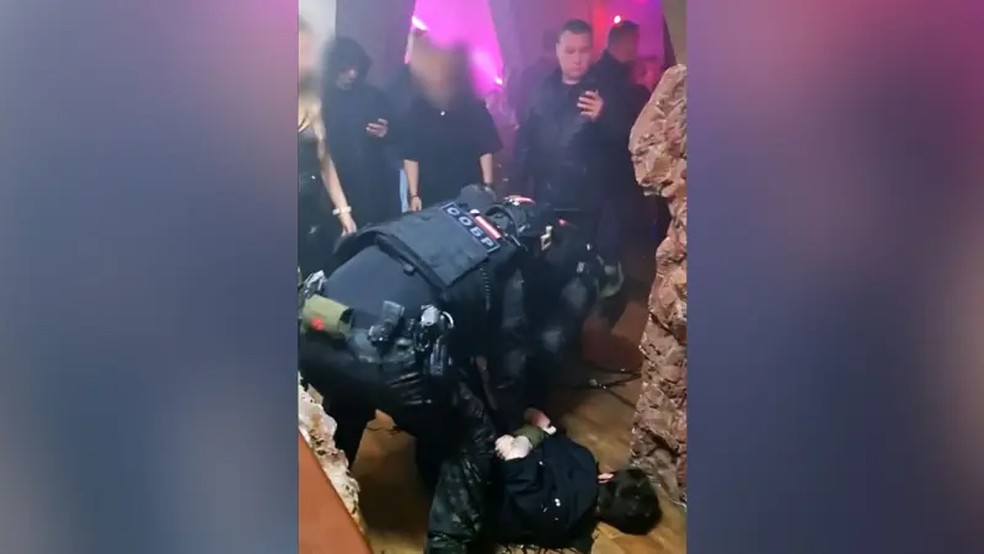 Agentes das forças de segurança (vistos na imagem imobilizando um convidado no chão) participaram da invasão à festa de Katya. — Foto: BBC