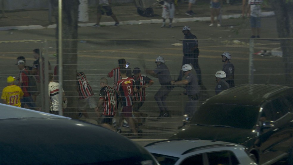 Policiais militares dão golpes de cassetete em torcedores do São Paulo neste domingo (24), do lado de fora do estádio do Morumbi, na Zona Sul da capital paulista. — Foto: Reprodução/Sportv