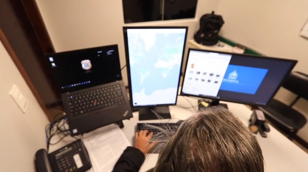Policial federal navega pelo sistema da Interpol de procurados — Foto: PF/Divulgação
