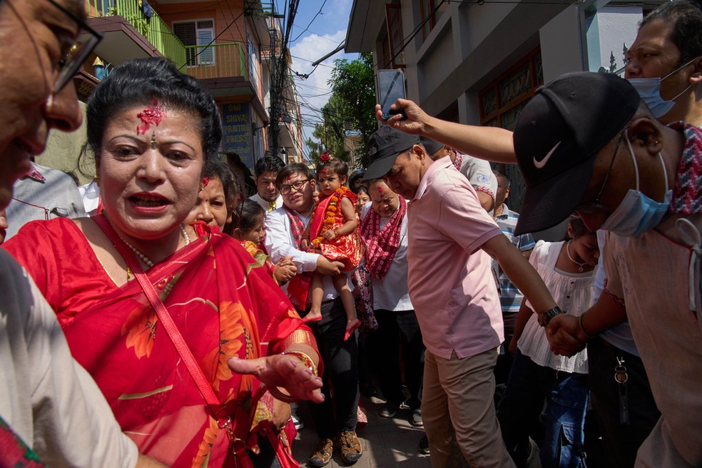 Aryatara Shakya, carregada por um membro de sua família durante caminhada até o Kumari Ghar, o palácio do templo onde ela residirá em Katmandu, — Foto: AP/Niranjan Shrestha