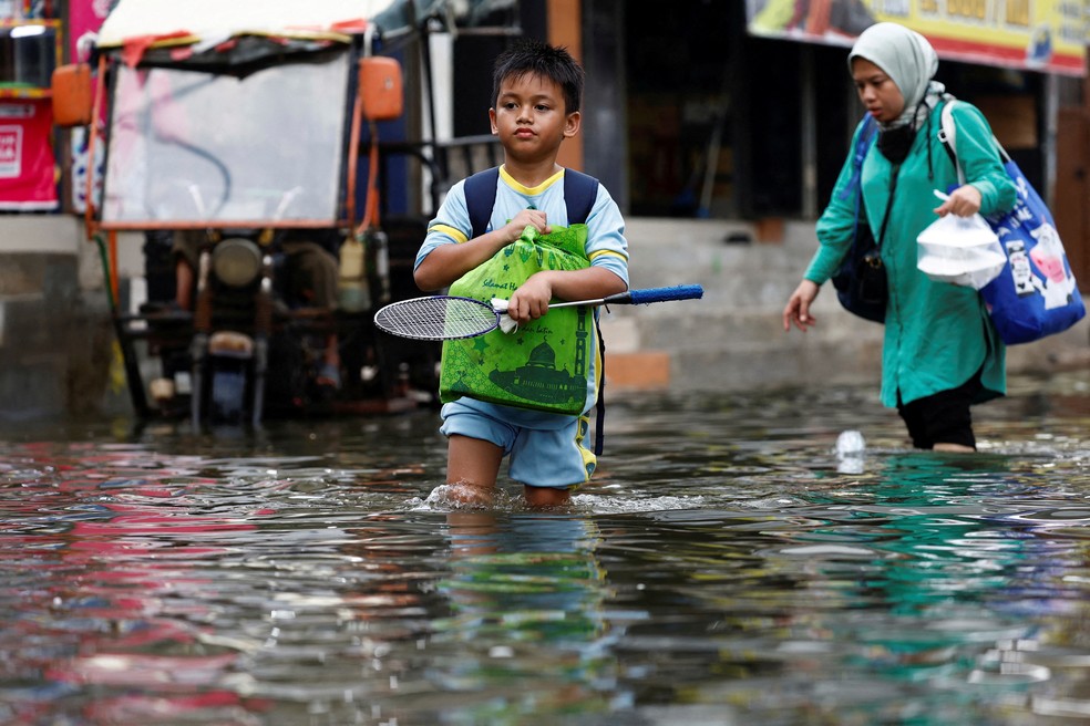 Moradores caminham por área alagada em Jacarta, onde a elevação do nível do mar e o afundamento do solo agravam inundações em novembro de 2024. — Foto: REUTERS/Willy Kurniawan