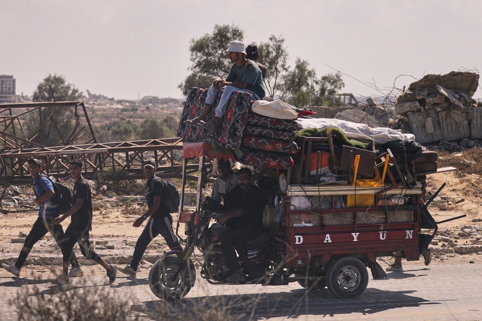 Palestinos deslocados caminham pela estrada costeira em direção à Cidade de Gaza, após Israel e Hamas concordarem em interromper a guerra e libertar os reféns, em 10 de outubro de 2025 — Foto: AP Photo/Yousef Al Zanoun
