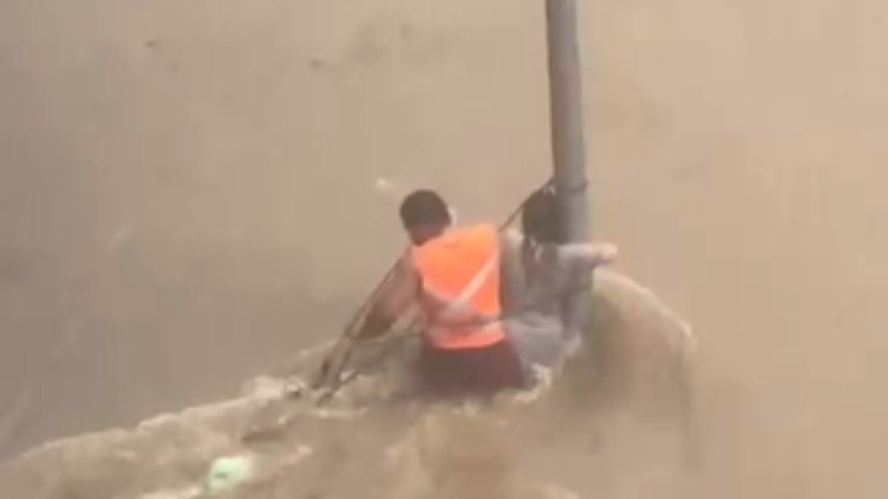 Uma mulher precisou se segurar em um poste na Avenida Afonso Vergueiro, em Sorocaba (SP) para não ser levada pela forte chuva que atingiu a cidade neste sábado (7). — Foto: Reprodução/