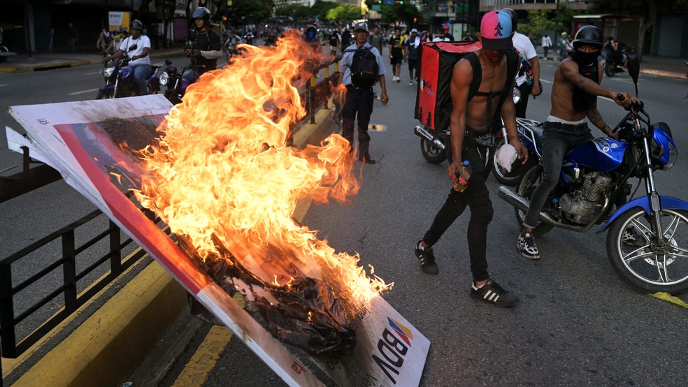 Manifestantes queimam banner durante protesto em Caracas, no dia 30 de julho de 2024, um dia aps a eleio presidencial na Venezuela — Foto: Yuri Cortez/AFP