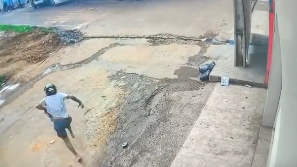 Após ser atropelado, o motociclista levanta, saca uma arma e dispara contra os suspeitos do carro. — Foto: Reprodução