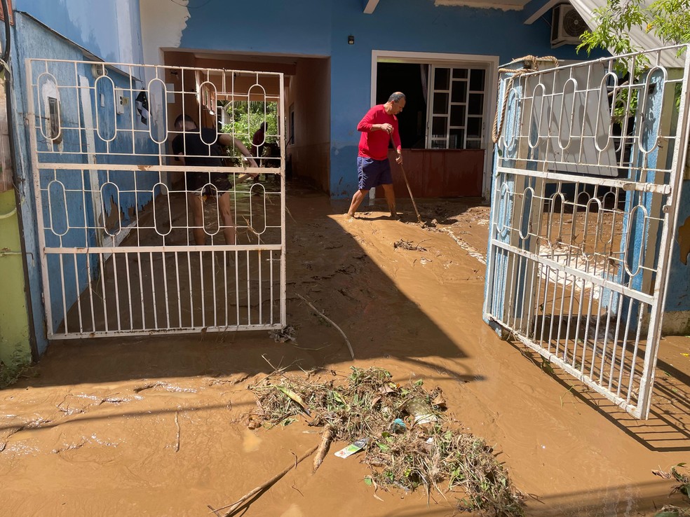 Moradores limpando casa após temporal em Paracambi — Foto: Iandra Rocha/g1