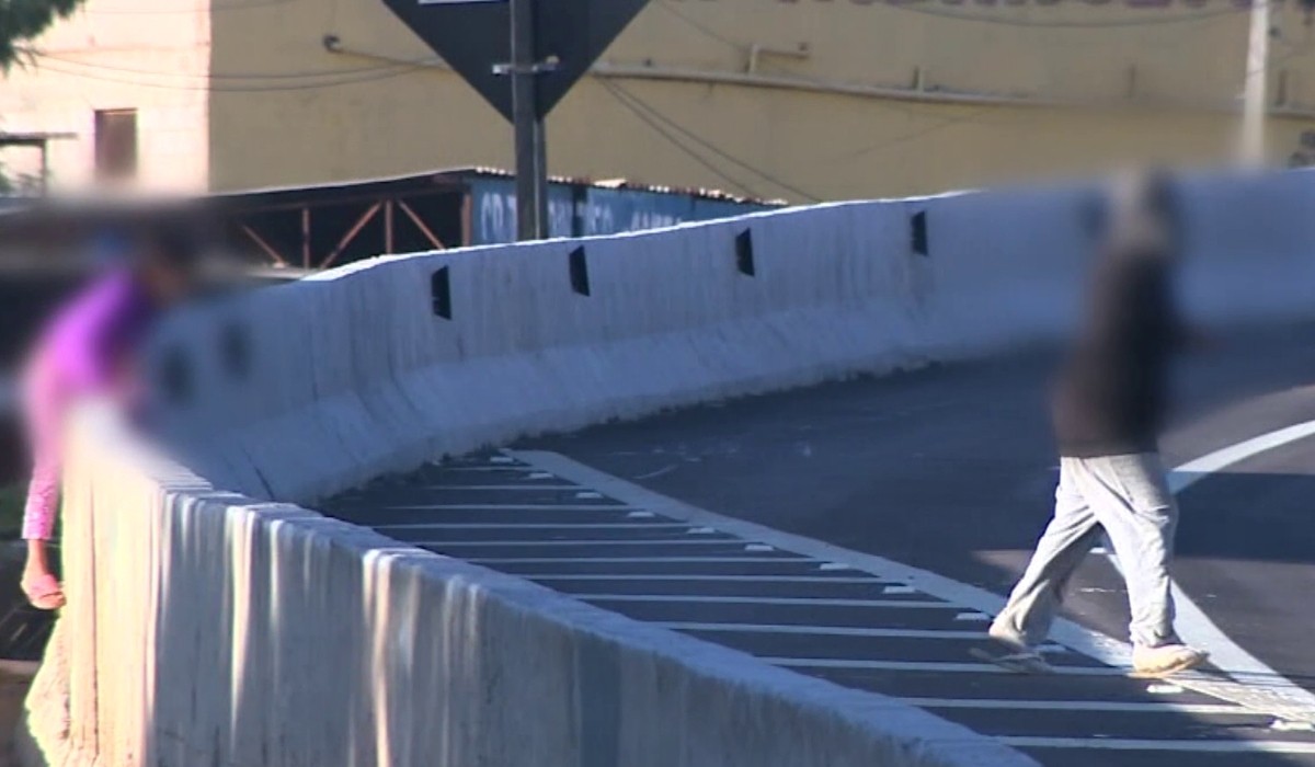 Sem passarela, moradores do entorno da Miguel Melhado pulam barreira e se arriscam para atravessar a pista