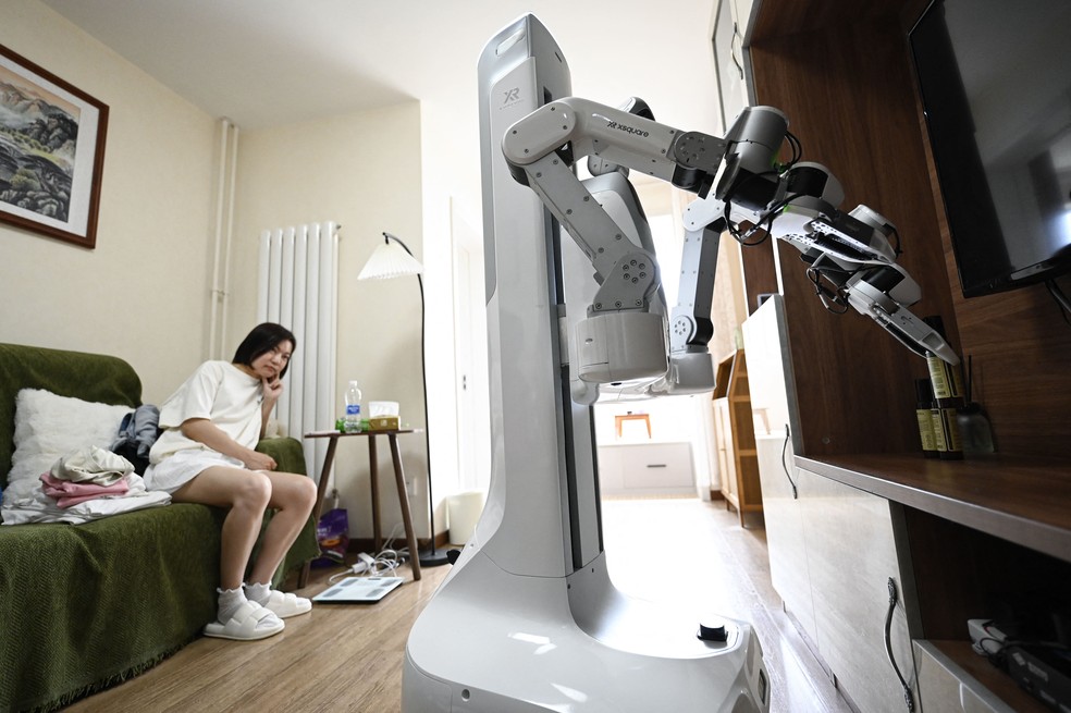 Foto, tirada em 21 de maio de 2026, mostra um robô da X Square organizando itens em uma prateleira na casa de um cliente em Pequim. — Foto: WANG ZHAO/AFP