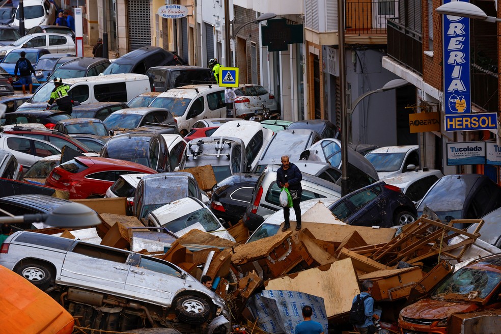 Homem caminha sobre carros arrastados por enchente histórica em Sedavi, Valência, na Espanha, em 31 de outubro de 2024 — Foto: Reuters/Susana Vera