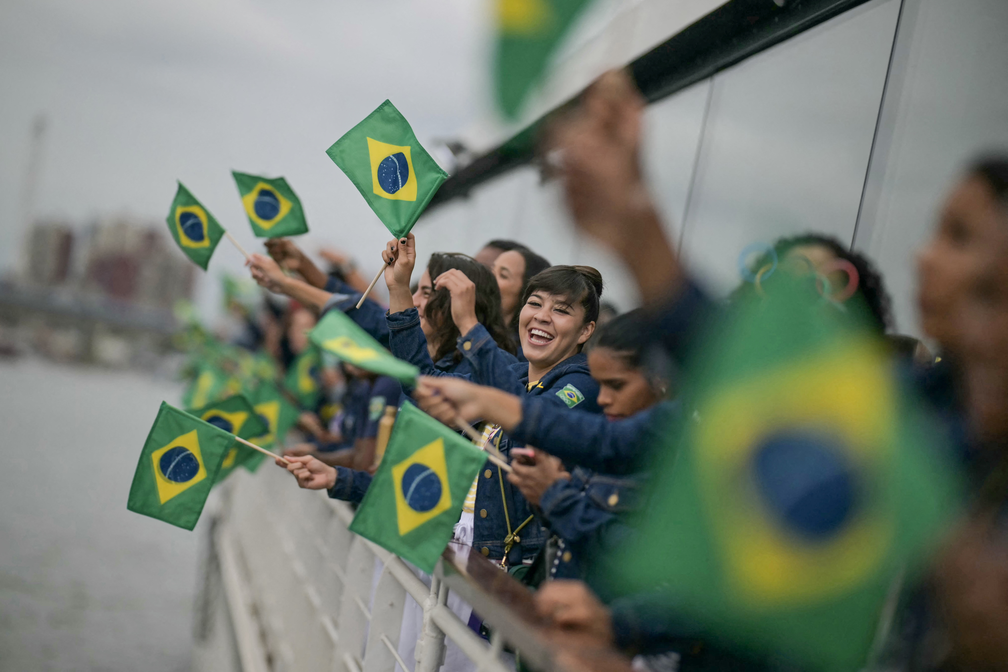 Atletas da delegação brasileira agitam bandeiras brasileiras enquanto navegam em um barco pelo rio Sena no início da cerimônia de abertura dos Jogos Olímpicos de Paris 2024 — Foto: Carl De Souza/via Reuters