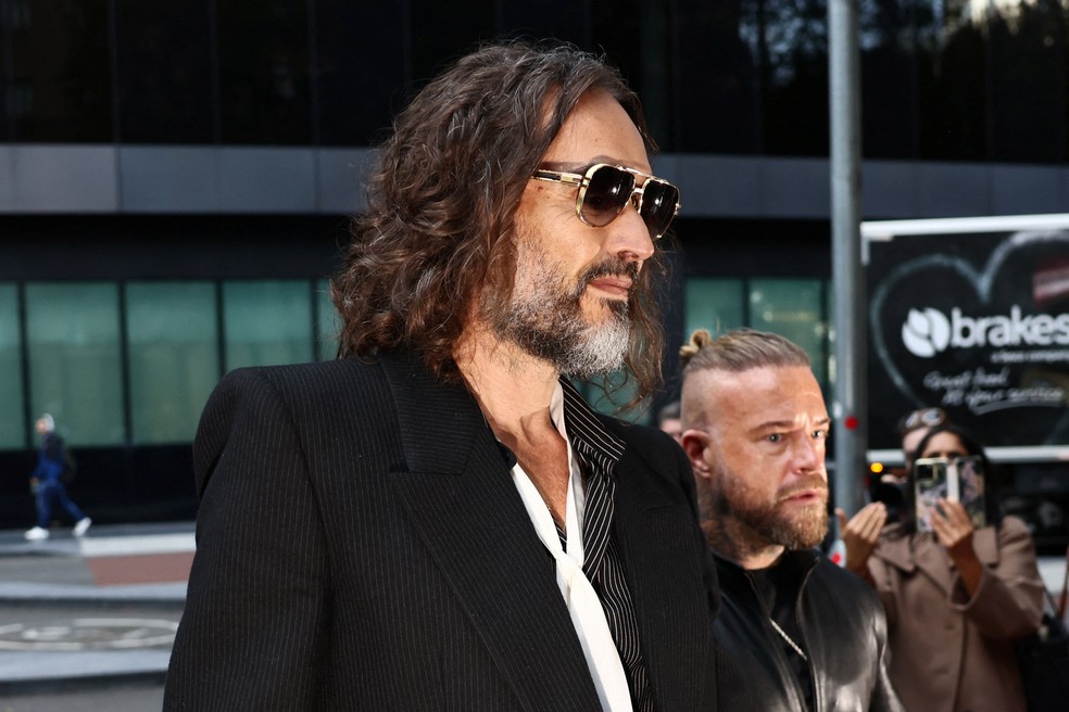 O ator e comediante britânico Russell Brand chega ao Tribunal da Coroa de Southwark, onde será julgado por acusações de estupro e agressão sexual envolvendo seis mulheres entre 1999 e 2009, acusações que ele nega, em Londres, Grã-Bretanha, em 14 de outubro de 2026. — Foto: REUTERS/Jack Taylor