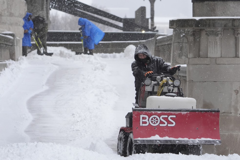 Trabalhadores limpam calçada em St. Louis, Missouri, no domingo (5) — Foto: Jeff Roberson/AP