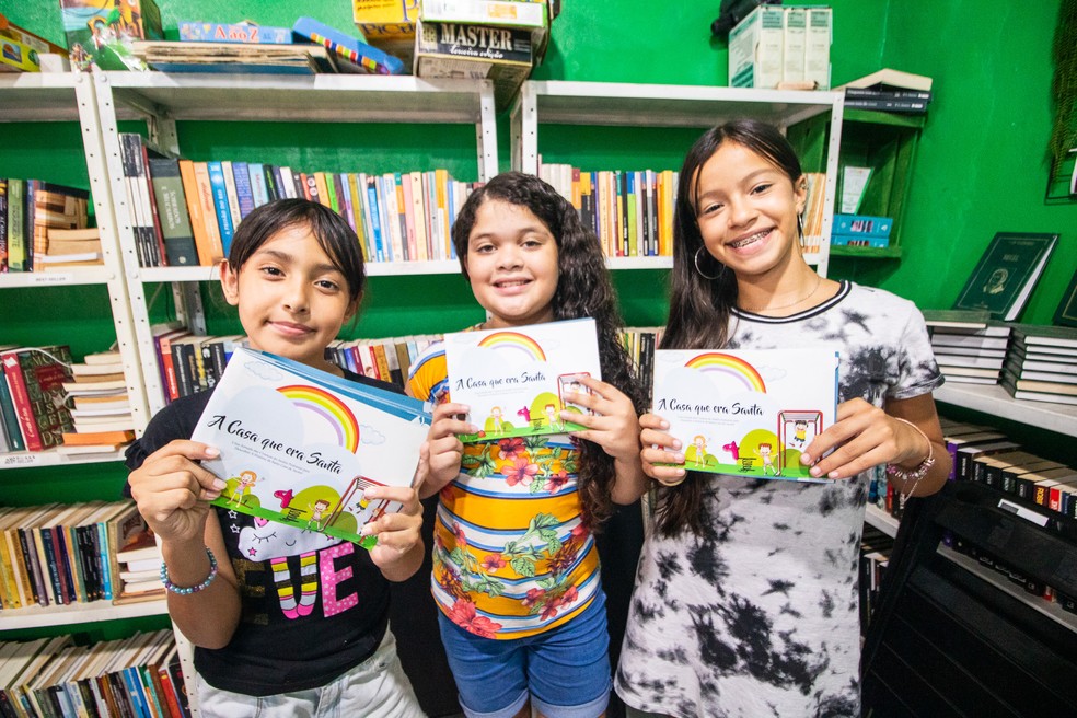 Crianças mostram com orgulho o livro que escreveram — Foto: Danilo Sardinha/g1