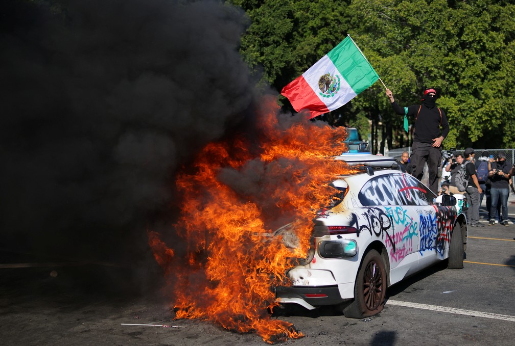 Manifestantes ateiam fogo em carros durante protesto contra as políticas de imigração de Donald Trump — Foto: REUTERS/Daniel Cole