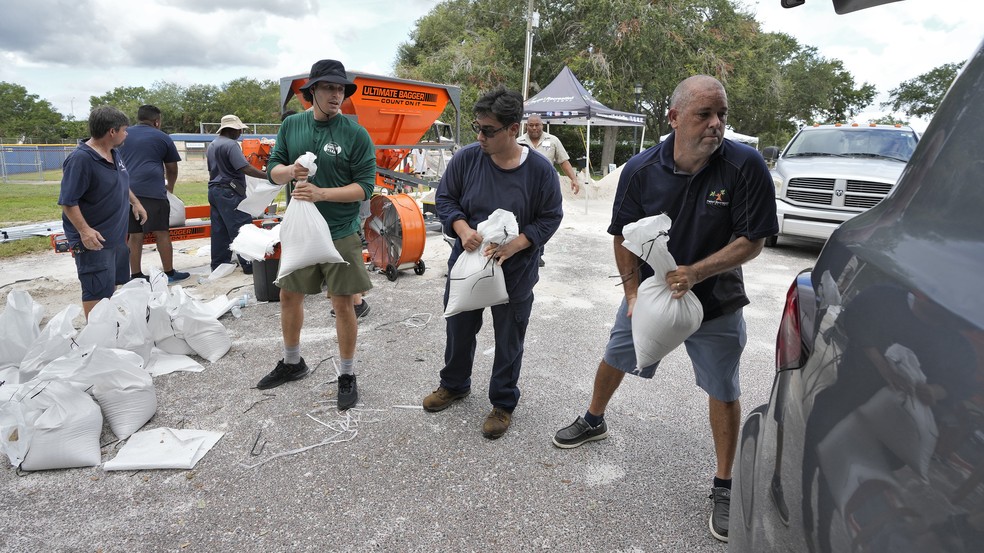 Funcionários de parque em Tampa ajudam moradores a encherem sacos de areia antes da chegada da tempestade Idália em 28 de agosto de 2023 — Foto: Chris O'Meara/AP