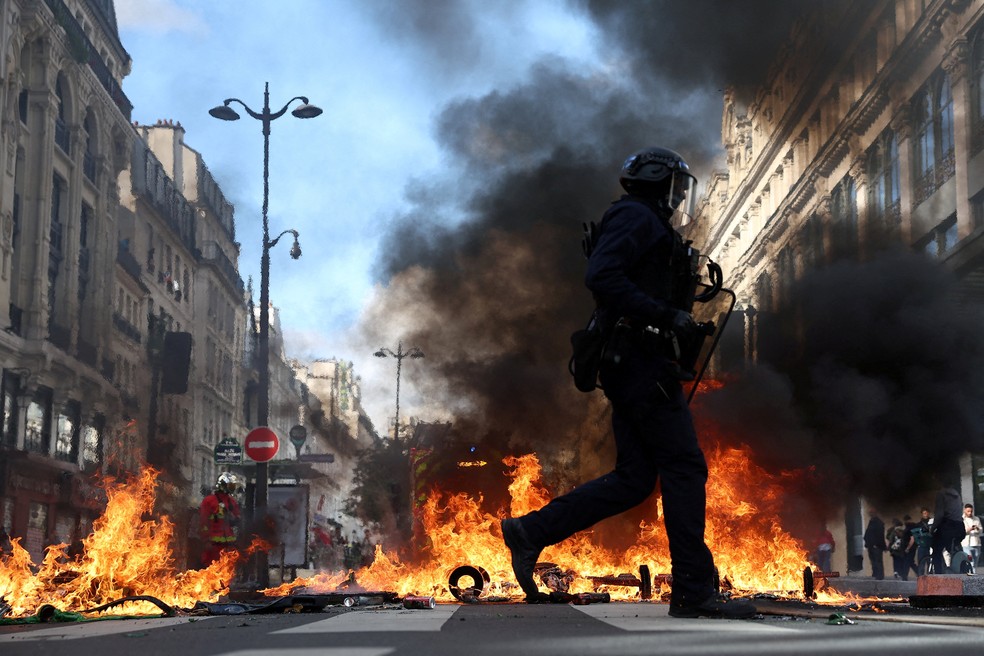  Policiais passam por objetos em chamas durante protesto contra o alto custo de vida em Paris. — Foto: Reuters