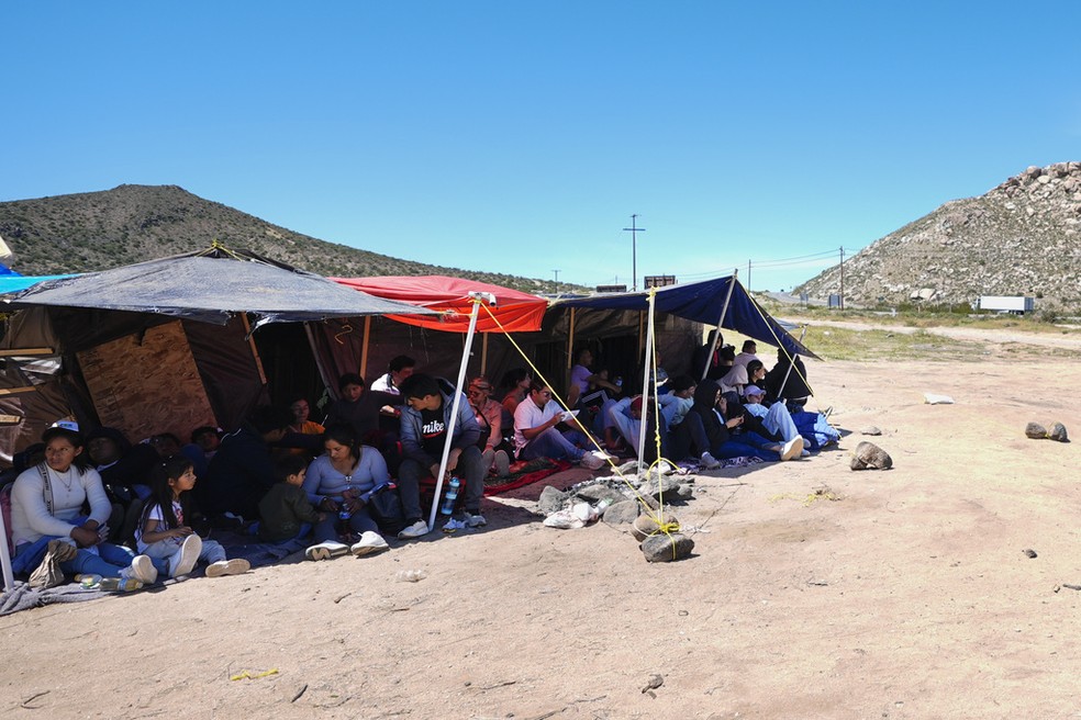 Grupo de migrantes aguarda em tenda no sul da Califórnia após cruzar ilegalmente a fronteira entre o México e Estados Unidos, em abril de 2024. — Foto: Gregory Bull/ AP